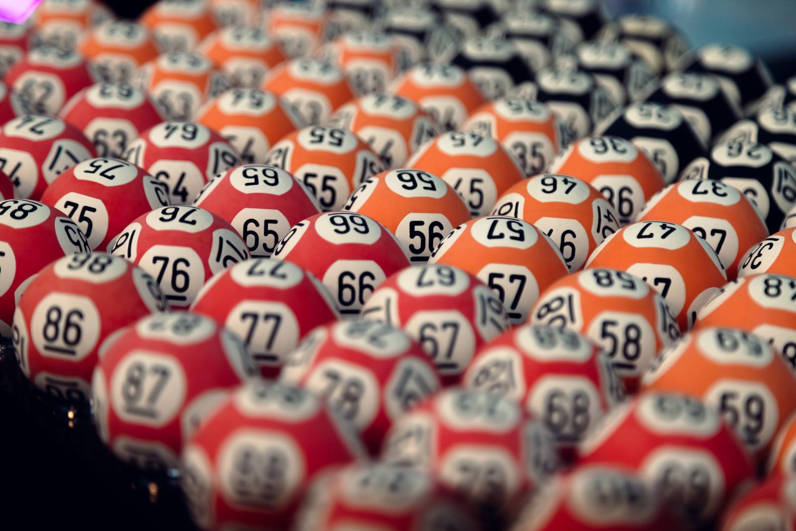 Numbered red and orange lotto balls lined up in their tray before a draw