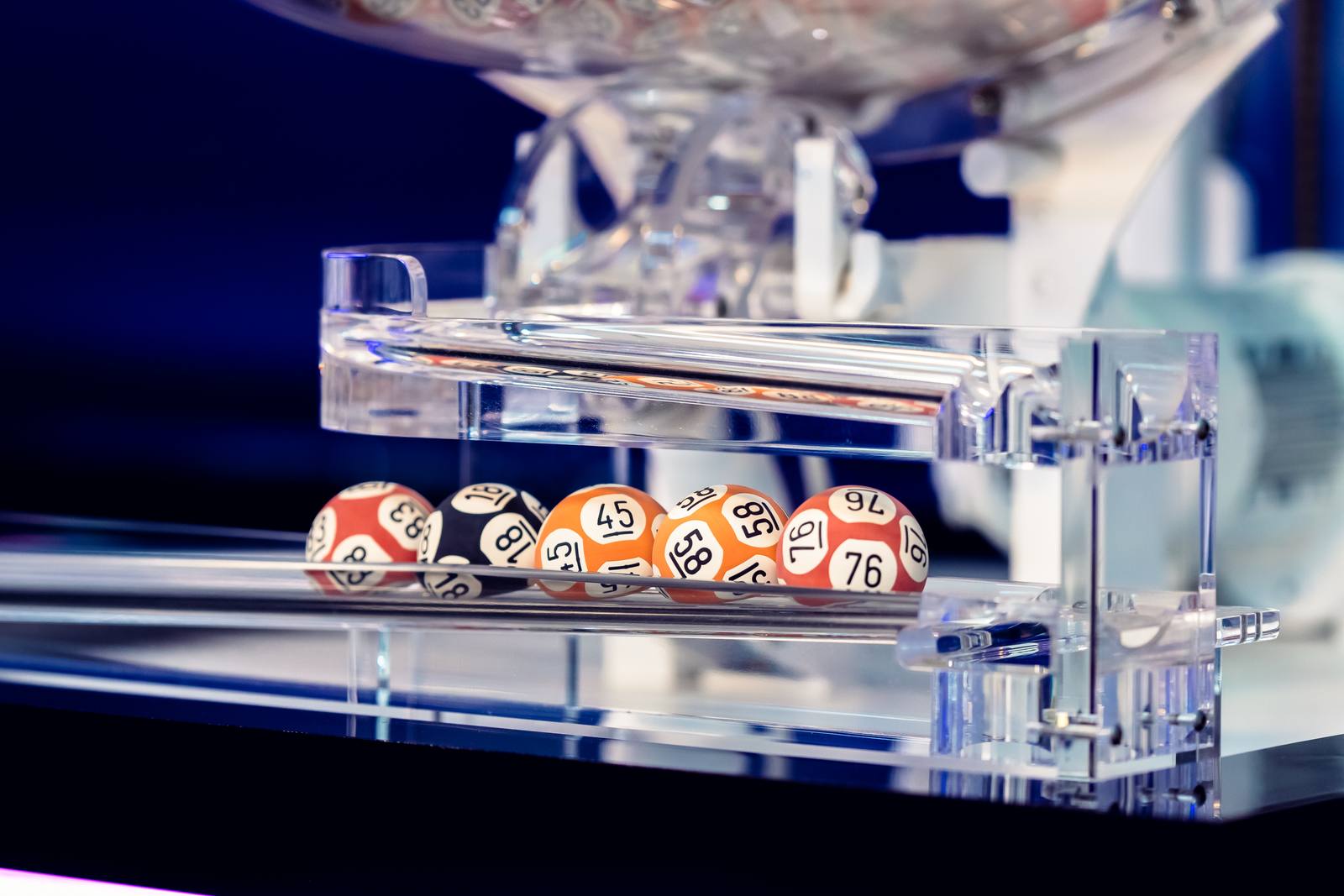 Five drawn balls, 83, 18, 45, 58 and 76, resting in the tray beneath a draw machine in the Alpha Lotto studio